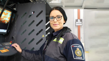 Image of Une agente devant un panneau de contrôle avec de l’équipement visible à proximité »