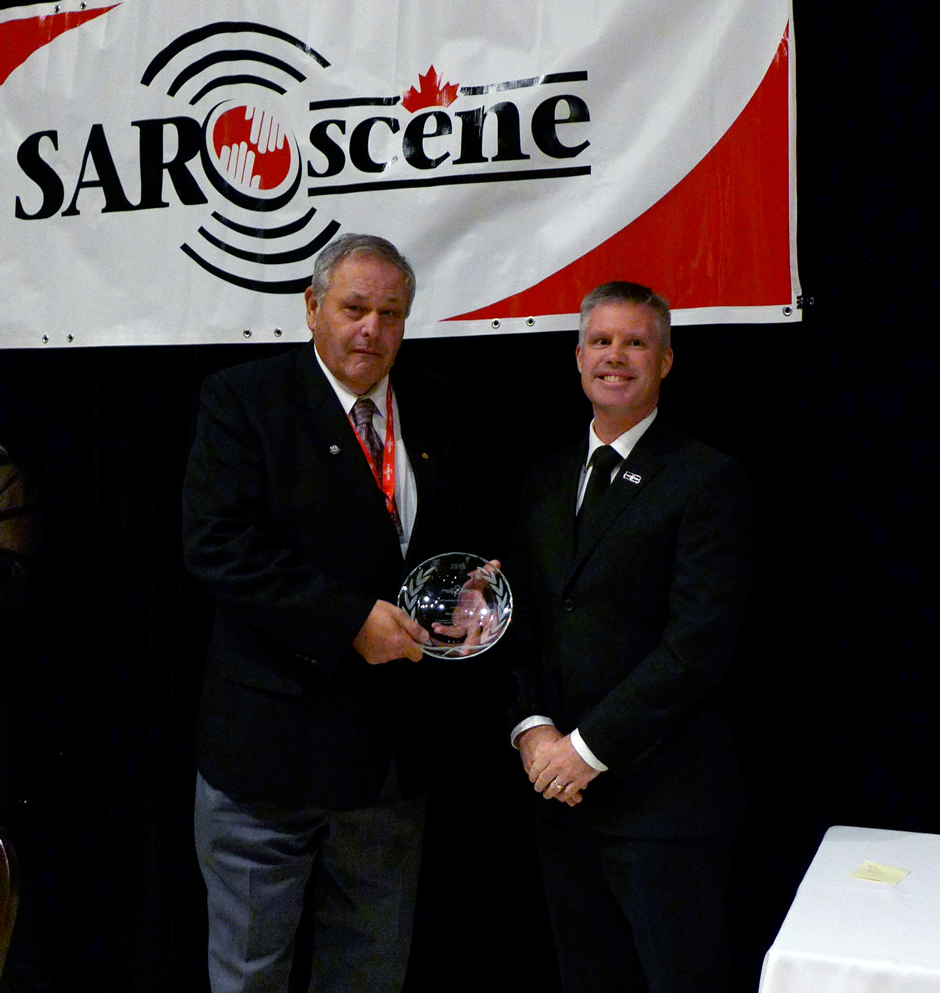Dominik Breton, Directeur, Secrétariat national Recherche et sauvetage, remet le Prix d'excellence en recherche et sauvetage en recherche à Roland Hanel membre des Services des incendies d'Ottawa.  Banquet de remise des prix à la conférence SARscène, le 25 octobre  2015.